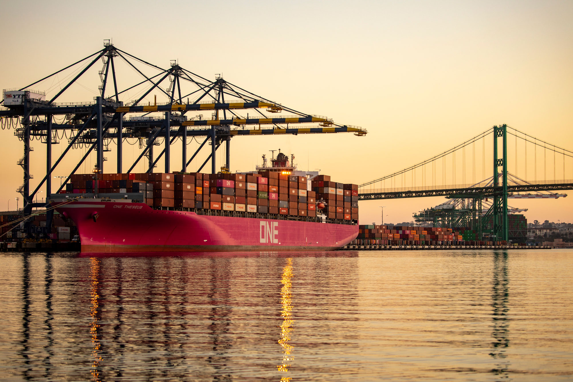 A container ship alongside cranes in the West Basin at the Port of Los Angeles in early morning light.